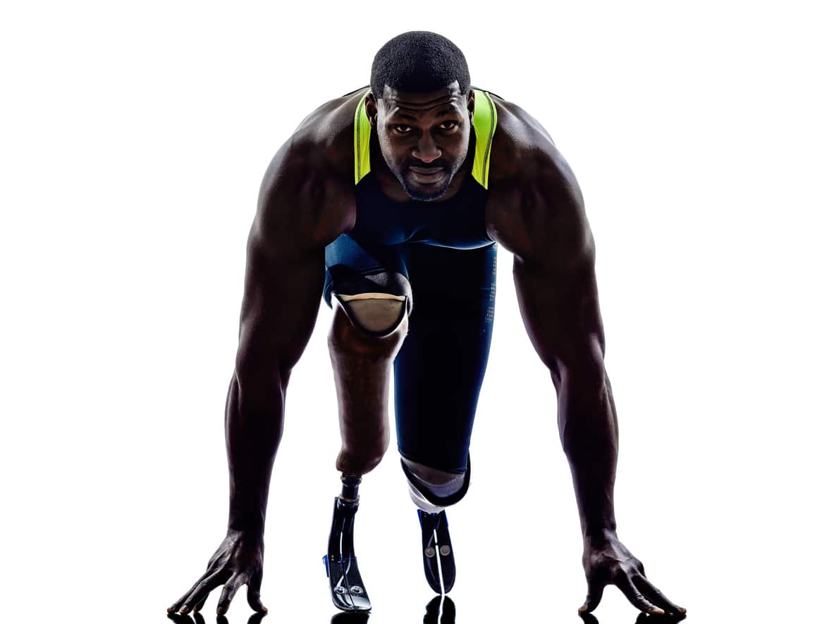 A black athlete takes his starting position for a race with prosthetic running blades attached