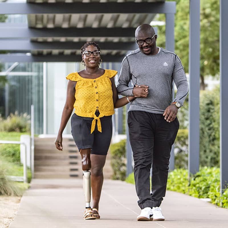 couple walking in a park, woman has a prosthetic leg